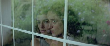 Movie still from “Dogtooth” (2009), directed by Yorgos Lanthimos – A woman looking out of a window at the camera; Close Up shot, Low angle