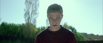 Movie still from “Dogtooth” (2009), directed by Yorgos Lanthimos – A young man is looking at the camera; Close Up shot, Low angle