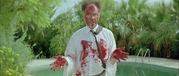 Movie still from “Dogtooth” (2009), directed by Yorgos Lanthimos – A man in a white dress shirt and tie covered in red paint; Medium shot, Overhead angle