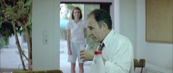 Movie still from “Dogtooth” (2009), directed by Yorgos Lanthimos – A man and a woman standing in front of a window; Medium shot, Over the shoulder angle