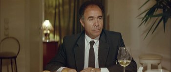 Movie still from “Dogtooth” (2009), directed by Yorgos Lanthimos – A man sitting at a table with a glass of white wine; Close Up shot, Over the shoulder angle