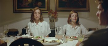 Movie still from “Dogtooth” (2009), directed by Yorgos Lanthimos – Two people sitting at a table with plates of food; Medium shot, Over the shoulder angle