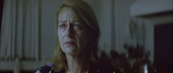 Movie still from “Dogtooth” (2009), directed by Yorgos Lanthimos – An older woman is crying in a dark room; Close Up shot, Low angle