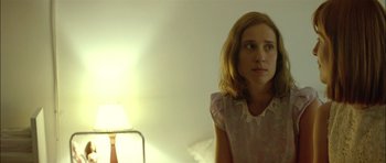 Movie still from “Dogtooth” (2009), directed by Yorgos Lanthimos – A young girl sitting on a bed in front of a lamp; Close Up shot, Low angle