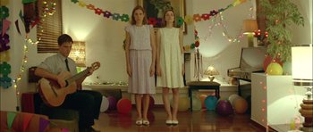 Movie still from “Dogtooth” (2009), directed by Yorgos Lanthimos – Two young women standing in a living room with balloons; Wide shot, Low angle