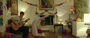 Movie still from “Dogtooth” (2009), directed by Yorgos Lanthimos – A woman is doing a yoga pose in front of a fireplace; Wide shot, Low angle