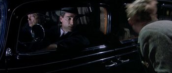 Movie still from “Dogville” (2003), directed by Lars von Trier – A man sitting in the back seat of a black car; Close Up shot, High angle
