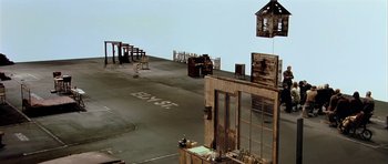 Movie still from “Dogville” (2003), directed by Lars von Trier – An old building with a lot of furniture on the ground; Extreme Wide shot, High angle