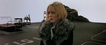 Movie still from “Dogville” (2003), directed by Lars von Trier – A woman with blonde hair wearing a black coat and a fur collar; Close Up shot, Over the shoulder angle