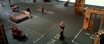 Movie still from “Dogville” (2003), directed by Lars von Trier – A couple of people that are standing in a room; Wide shot, High angle