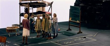 Movie still from “Dogville” (2003), directed by Lars von Trier – A group of people standing on a stage; Wide shot, High angle