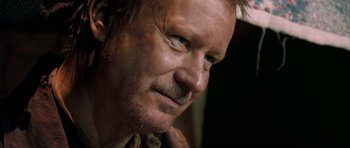Movie still from “Dogville” (2003), directed by Lars von Trier – A man's face in a dark room; Close Up shot, Over the shoulder angle
