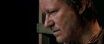 Movie still from “Dogville” (2003), directed by Lars von Trier – A man's face in a dark room; Close Up shot, Low angle