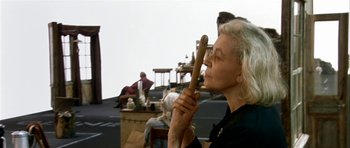 Movie still from “Dogville” (2003), directed by Lars von Trier – An older woman holding a wooden stick up to her face; Medium shot, Over the shoulder angle