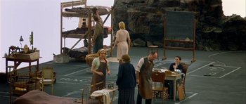 Movie still from “Dogville” (2003), directed by Lars von Trier – A group of people standing around a room; Wide shot, High angle