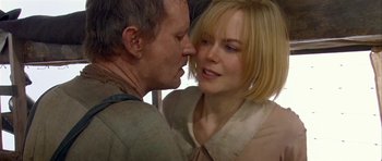 Movie still from “Dogville” (2003), directed by Lars von Trier – A man and a woman kissing each other in front of a window; Close Up shot, Over the shoulder angle