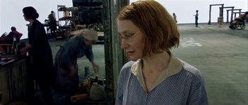 Movie still from “Dogville” (2003), directed by Lars von Trier – A woman wearing glasses looking at something on the ground; Close Up shot, Over the shoulder angle