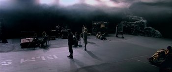 Movie still from “Dogville” (2003), directed by Lars von Trier – A group of people standing on top of a cement floor; Extreme Wide shot, High angle