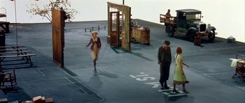 Movie still from “Dogville” (2003), directed by Lars von Trier – A man and a woman are standing in a parking lot; Wide shot, High angle