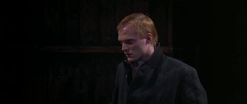 Movie still from “Dogville” (2003), directed by Lars von Trier – A man in a black coat and a red tie; Medium shot, Over the shoulder angle