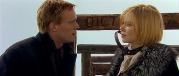 Movie still from “Dogville” (2003), directed by Lars von Trier – A man and a woman standing next to each other on a bench; Close Up shot, Over the shoulder angle
