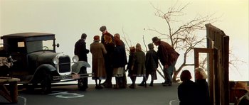 Movie still from “Dogville” (2003), directed by Lars von Trier – A group of people standing on the side of a road; Wide shot, High angle
