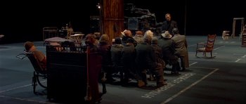 Movie still from “Dogville” (2003), directed by Lars von Trier – A group of people sitting around a table; Wide shot, High angle