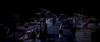 Movie still from “Dogville” (2003), directed by Lars von Trier – A group of people standing on the side of a road; Extreme Wide shot, High angle