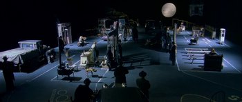 Movie still from “Dogville” (2003), directed by Lars von Trier – A group of people standing around in a dark room; Extreme Wide shot, High angle