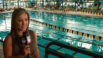 Movie still from “Dolphin Tale” (2011), directed by Charles Martin Smith – A woman is holding a microphone in front of an indoor swimming pool; Medium shot, Over the shoulder angle