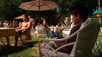 Movie still from “Dolphin Tale” (2011), directed by Charles Martin Smith – A group of people sitting around an outdoor table with an umbrella; Wide shot, High angle