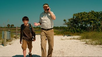Movie still from “Dolphin Tale” (2011), directed by Charles Martin Smith – An older man and a young boy walking on the beach; Medium shot, Low angle