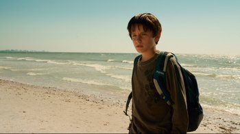 Movie still from “Dolphin Tale” (2011), directed by Charles Martin Smith – A boy with a backpack standing on the beach; Medium shot, Low angle