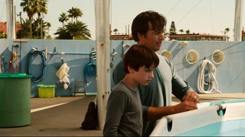 Movie still from “Dolphin Tale” (2011), directed by Charles Martin Smith – A man and a boy standing next to each other near a pool; Medium shot, Over the shoulder angle