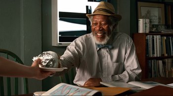 Movie still from “Dolphin Tale” (2011), directed by Charles Martin Smith – An older man holding a plate of food and smiling; Medium shot, Overhead angle