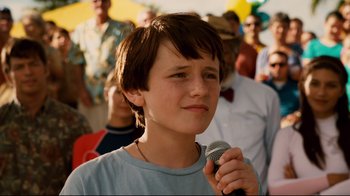 Movie still from “Dolphin Tale” (2011), directed by Charles Martin Smith – A young boy holding a microphone in front of a group of people; Close Up shot, Low angle
