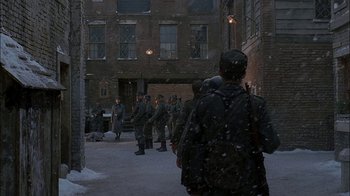 Movie still from “Dominion: Prequel to the Exorcist” (2005), directed by Paul Schrader – A group of people walking down a snowy sidewalk; Wide shot, Over the shoulder angle
