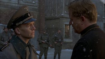 Movie still from “Dominion: Prequel to the Exorcist” (2005), directed by Paul Schrader – Two men in uniforms talking to each other in the snow; Close Up shot, Over the shoulder angle