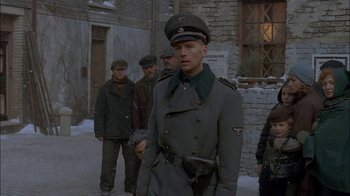 Movie still from “Dominion: Prequel to the Exorcist” (2005), directed by Paul Schrader – A group of men standing next to each other on a street; Medium shot, Over the shoulder angle