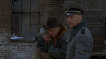 Movie still from “Dominion: Prequel to the Exorcist” (2005), directed by Paul Schrader – A man and a woman are standing next to a man in a uniform; Medium shot, Over the shoulder angle