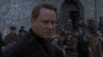 Movie still from “Dominion: Prequel to the Exorcist” (2005), directed by Paul Schrader – A man in a black shirt and a chain around his neck; Close Up shot, Over the shoulder angle