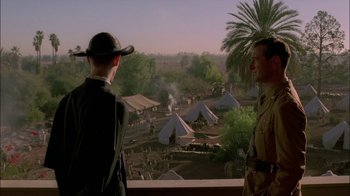 Movie still from “Dominion: Prequel to the Exorcist” (2005), directed by Paul Schrader – Two men are looking out over a camp site; Wide shot, Over the shoulder angle
