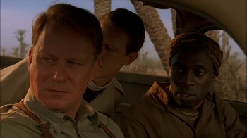 Movie still from “Dominion: Prequel to the Exorcist” (2005), directed by Paul Schrader – Three men are sitting in the back of a car; Close Up shot, Over the shoulder angle