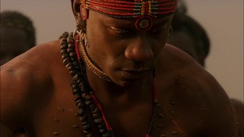 Movie still from “Dominion: Prequel to the Exorcist” (2005), directed by Paul Schrader – A person wearing beads and a necklace; Close Up shot, Low angle