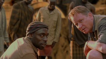 Movie still from “Dominion: Prequel to the Exorcist” (2005), directed by Paul Schrader – A group of men standing next to each other; Close Up shot, Over the shoulder angle