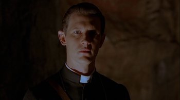 Movie still from “Dominion: Prequel to the Exorcist” (2005), directed by Paul Schrader – A man wearing a priest's collar and a priest's outfit; Close Up shot, Low angle