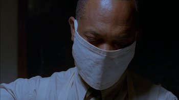 Movie still from “Dominion: Prequel to the Exorcist” (2005), directed by Paul Schrader – A man wearing a face mask with his eyes closed; Close Up shot, Low angle