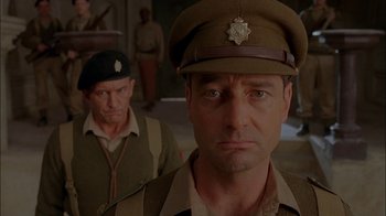 Movie still from “Dominion: Prequel to the Exorcist” (2005), directed by Paul Schrader – A man in a military uniform is looking at the camera while another man in a uniform looks at the camera; Close Up shot, Low angle