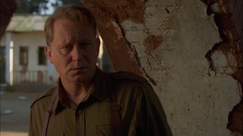 Movie still from “Dominion: Prequel to the Exorcist” (2005), directed by Paul Schrader – A person standing in front of a brick wall; Close Up shot, Low angle