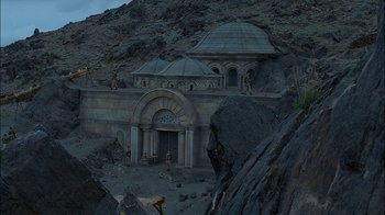 Movie still from “Dominion: Prequel to the Exorcist” (2005), directed by Paul Schrader – An image of a building in the middle of a mountain; Extreme Wide shot, Low angle